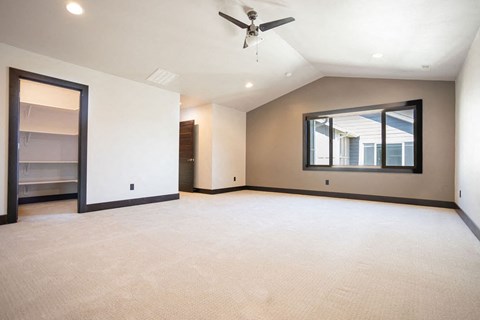 an empty living room with a ceiling fan and a window