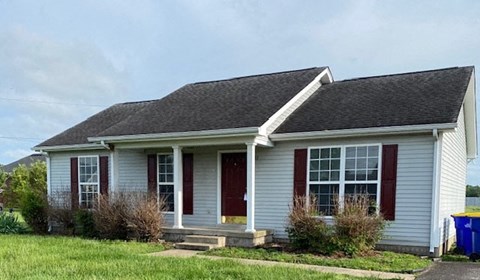 a white house with red shutters and a lawn