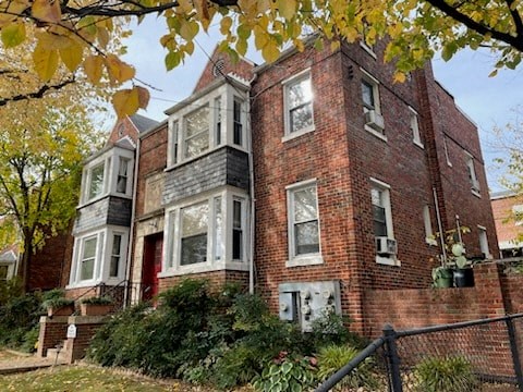 a red brick house with white windows and a fence