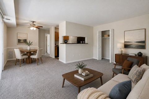 A living room with a couch, coffee table, and a dining table.