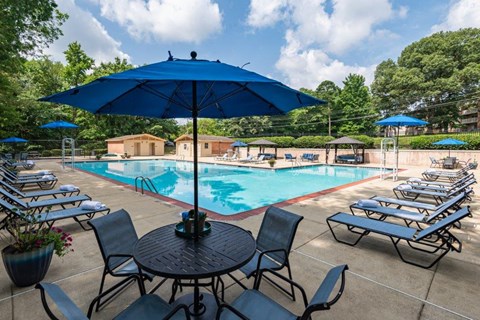 a swimming pool with tables and chairs under an umbrella