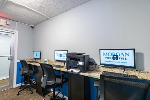 a office with three computers and a monitor on a desk