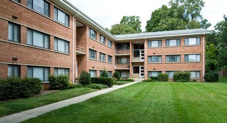 a large brick apartment building with a green yard
