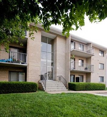 the exterior of an apartment building with stairs and grass