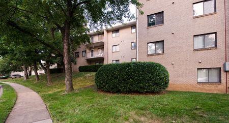 a brick apartment building with trees and a sidewalk