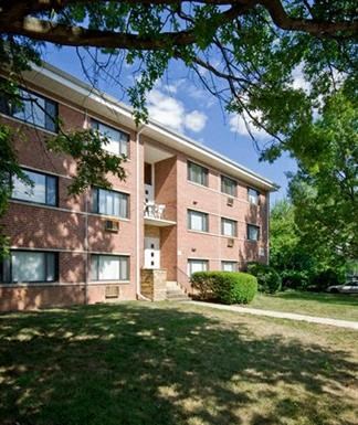 a brick apartment building with grass and trees