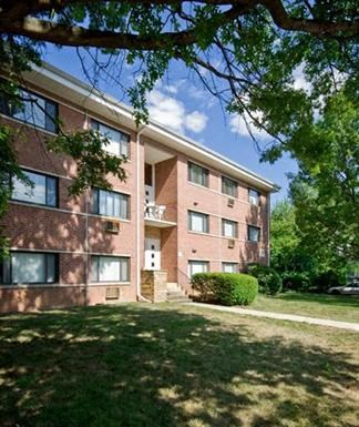 a brick apartment building with grass and trees
