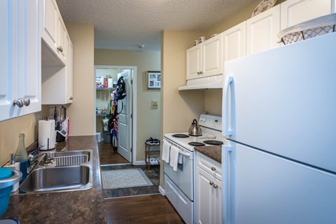 A kitchen with white cabinets and a white refrigerator.