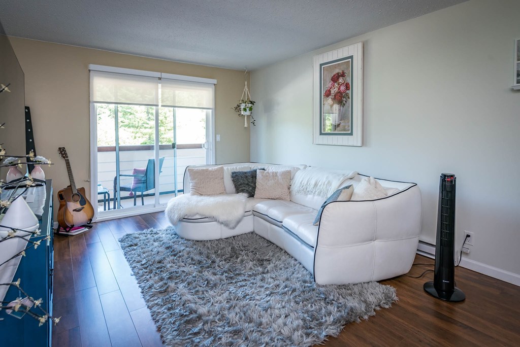 A living room with a white couch and a guitar on the floor.