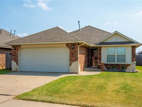 a brick house with a garage and a lawn