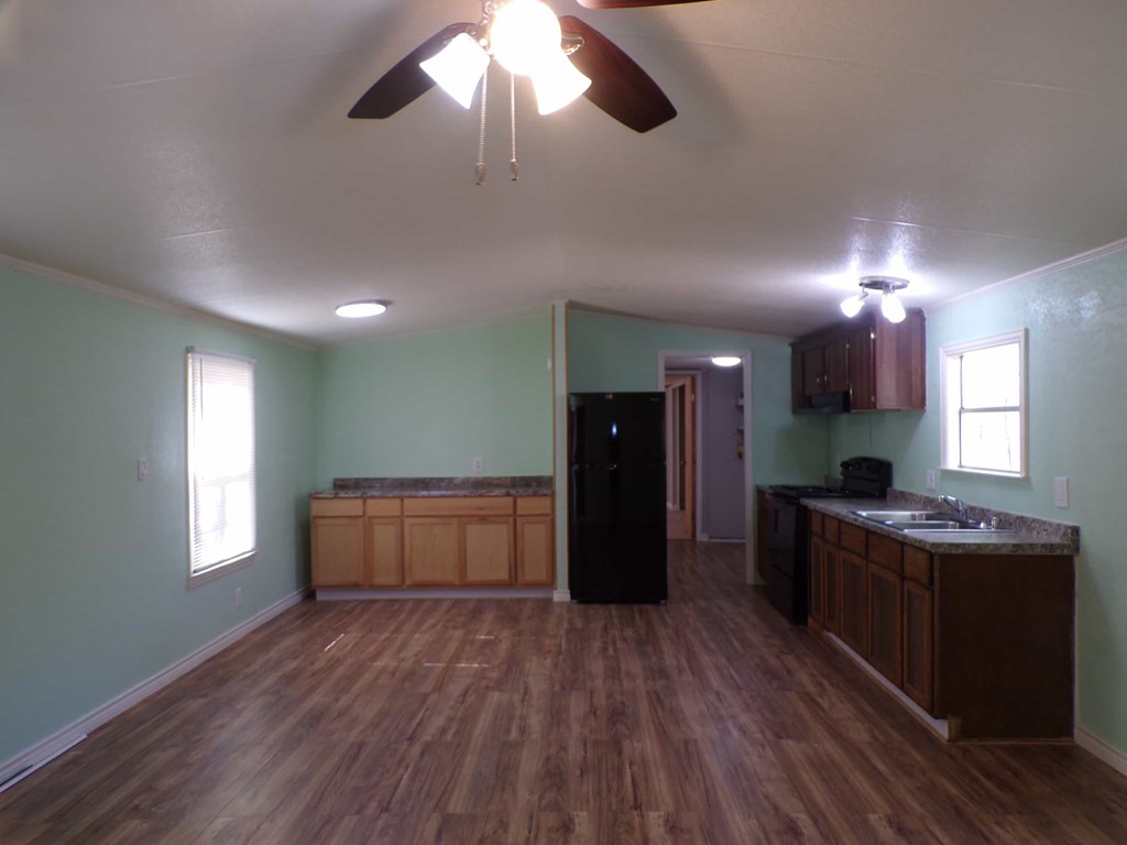 A kitchen with wood floors and a ceiling fan.