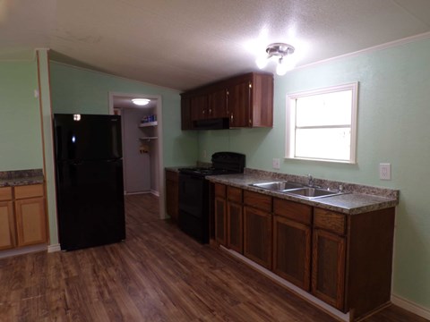 A kitchen with a black refrigerator and wooden cabinets.
