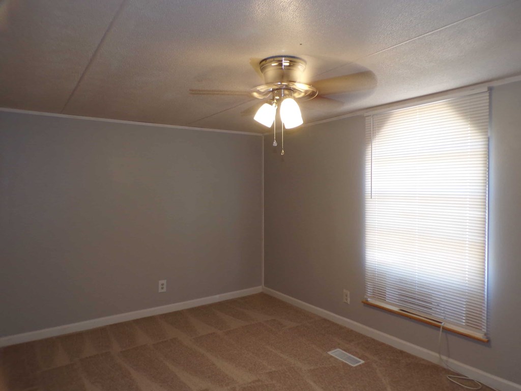 A room with a ceiling fan and a window with blinds.