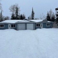 A house with a garage is surrounded by snow.