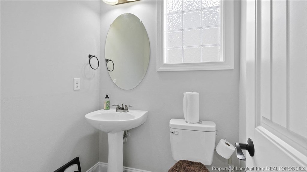 a white bathroom with a white sink and toilet and a mirror