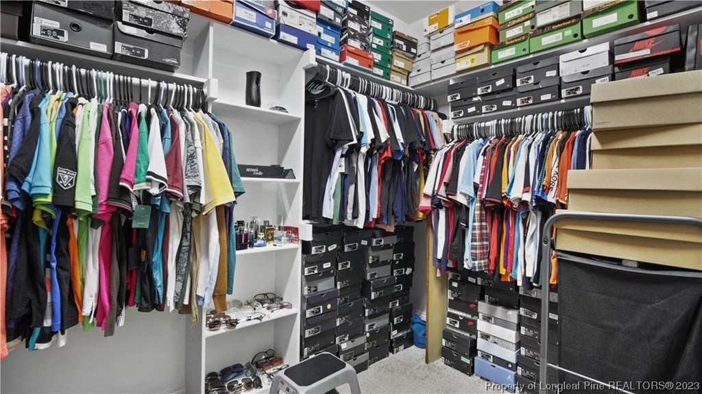 a walk in closet filled with clothes and shelves