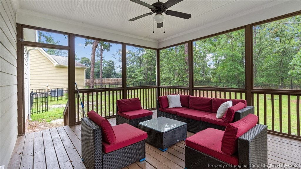 a covered porch with couches and chairs and a ceiling fan