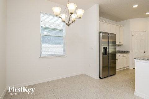 A kitchen with a stainless steel refrigerator and a chandelier.