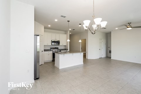 an open kitchen and living room with white cabinets and tile flooring
