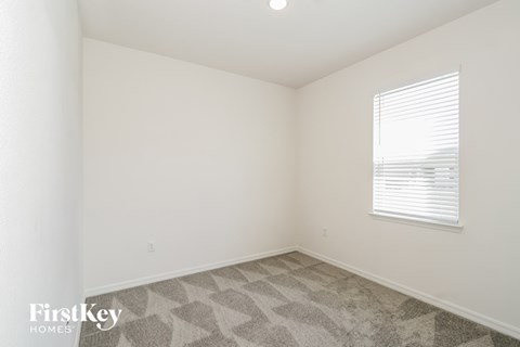 a bedroom with white walls and carpet and a window
