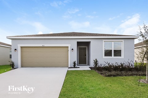 a white house with a garage door and a lawn
