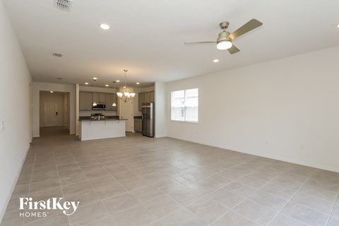 an empty living room and kitchen with a ceiling fan