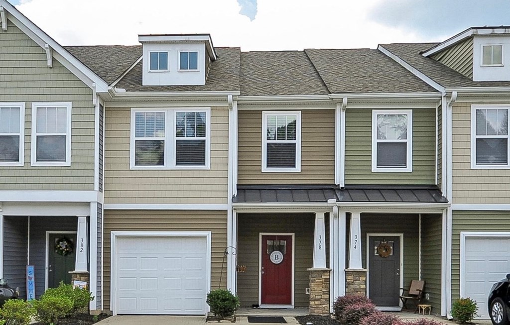 a yellow house with a red door and white garage doors