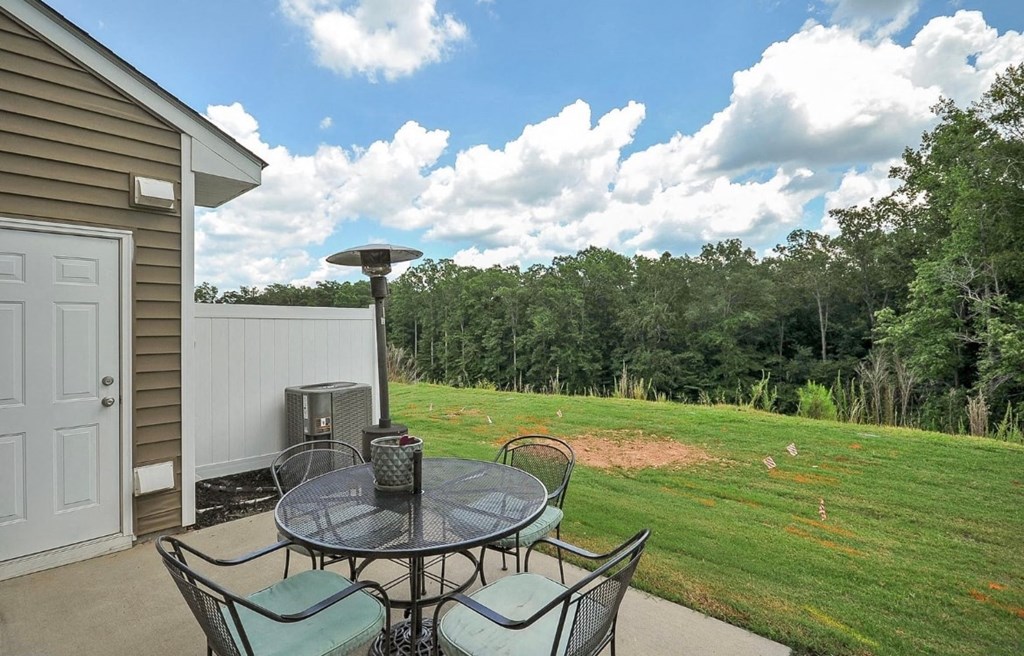 a patio with a table and chairs overlooking a grassy field