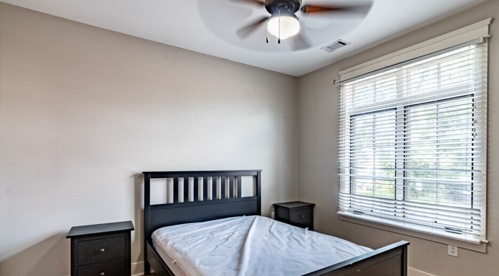 an empty bedroom with a bed and a ceiling fan