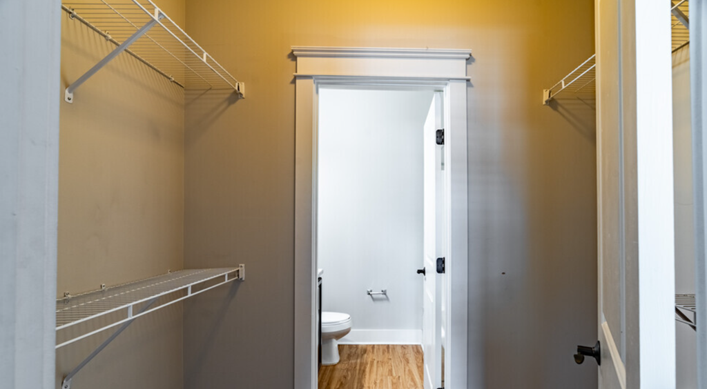 a walk in closet with a door open to a bathroom with a toilet