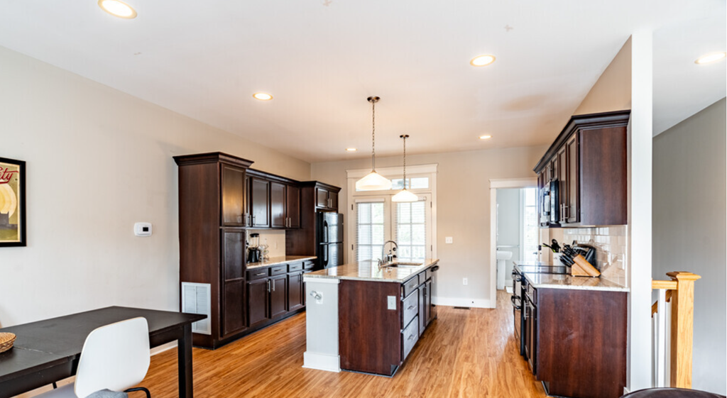 an open kitchen with dark wood cabinets and a large island