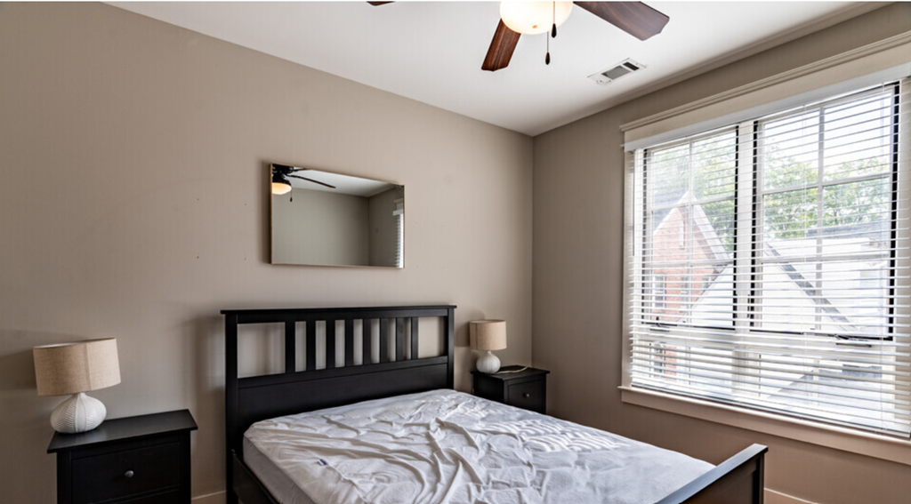 a bedroom with a bed and a ceiling fan and a window