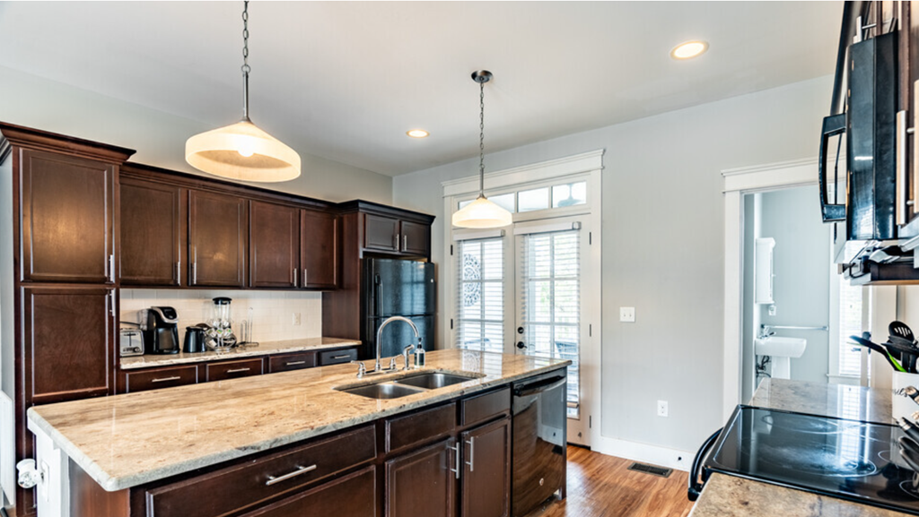 an open kitchen with dark wood cabinets and a marble counter top