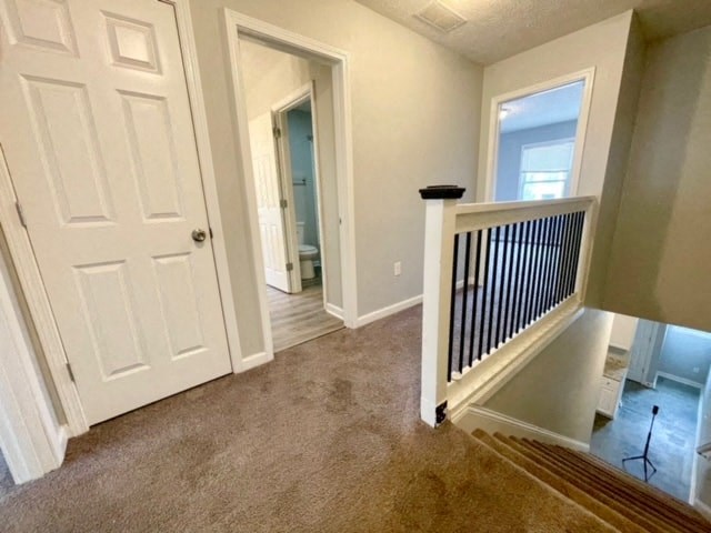 an empty hallway with a staircase and a door to a bathroom