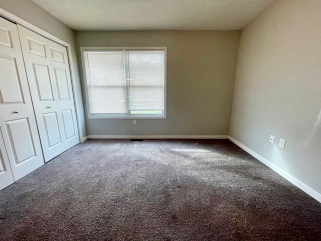 an empty room with carpet and a window and white doors
