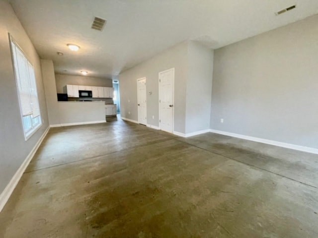 an empty living room and kitchen with white walls and wooden floors