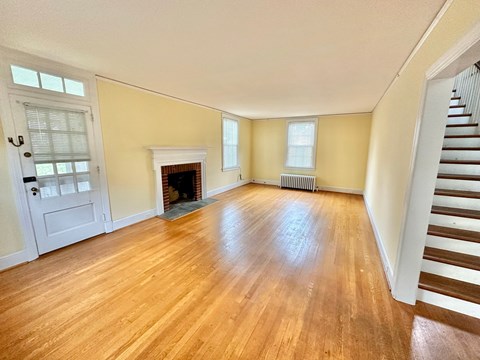 an empty living room with a fireplace and wooden floors