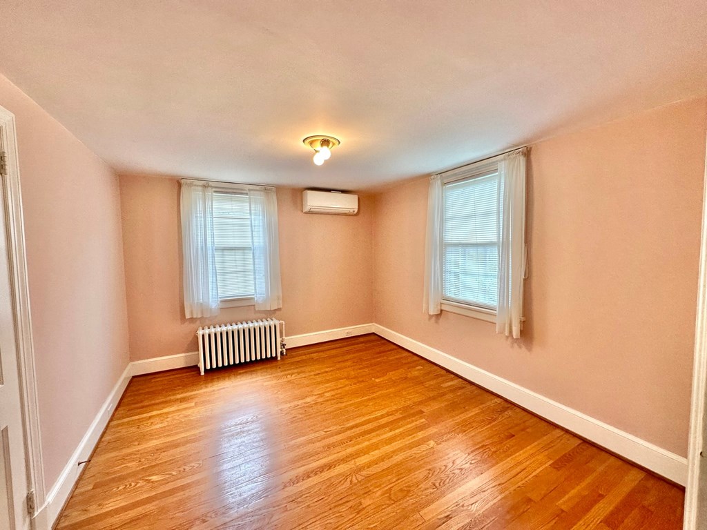 an empty room with a wood floor and two windows