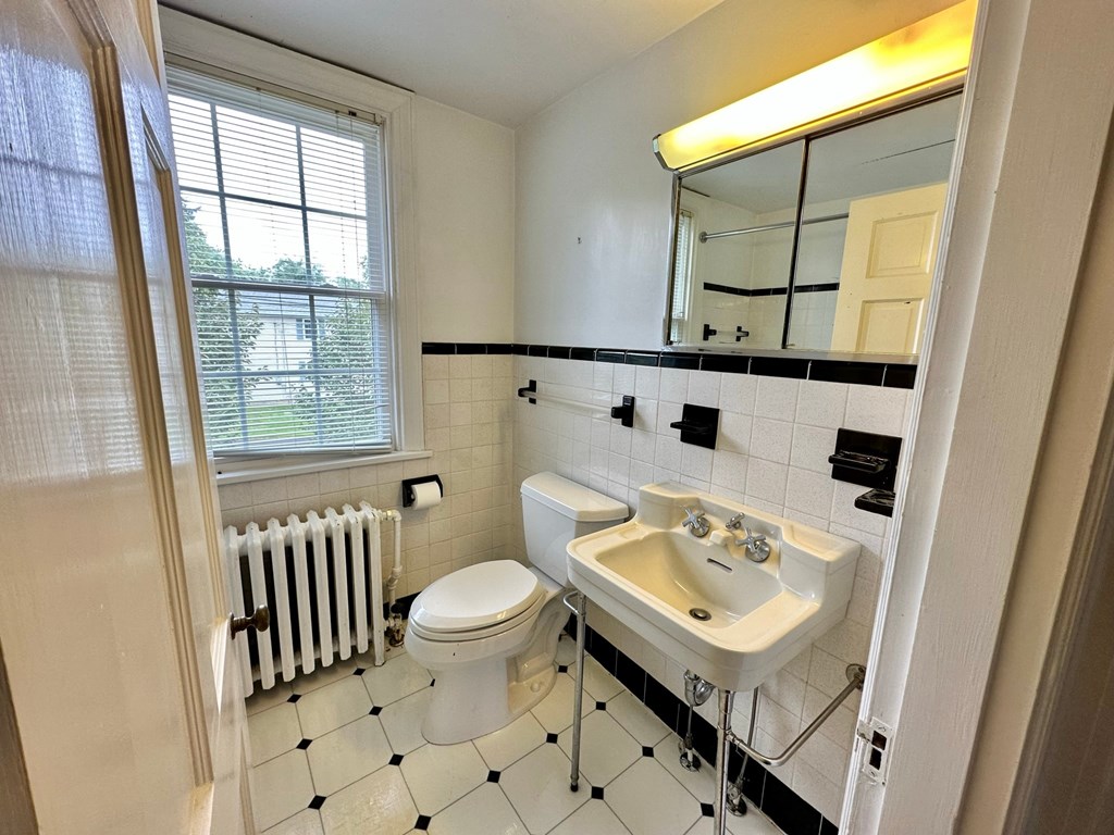 a bathroom with a sink toilet and a radiator