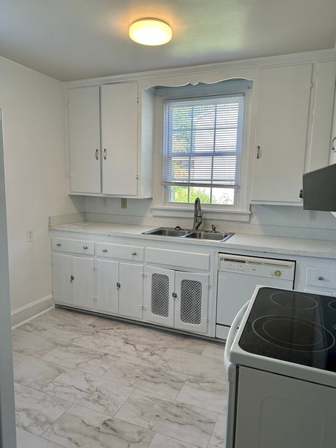 a kitchen with white cabinets and a sink and a window