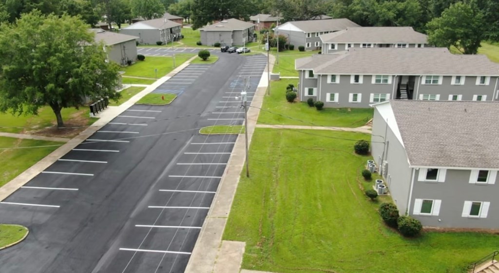 A parking lot in front of a building with a green lawn.