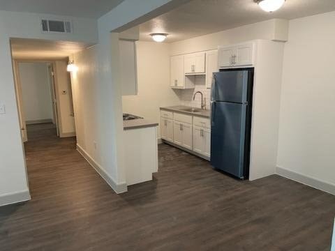A kitchen with a black fridge and white cabinets.