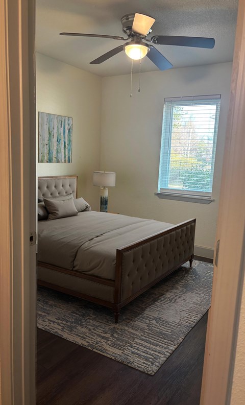 A bedroom with a bed, a ceiling fan, and a window.