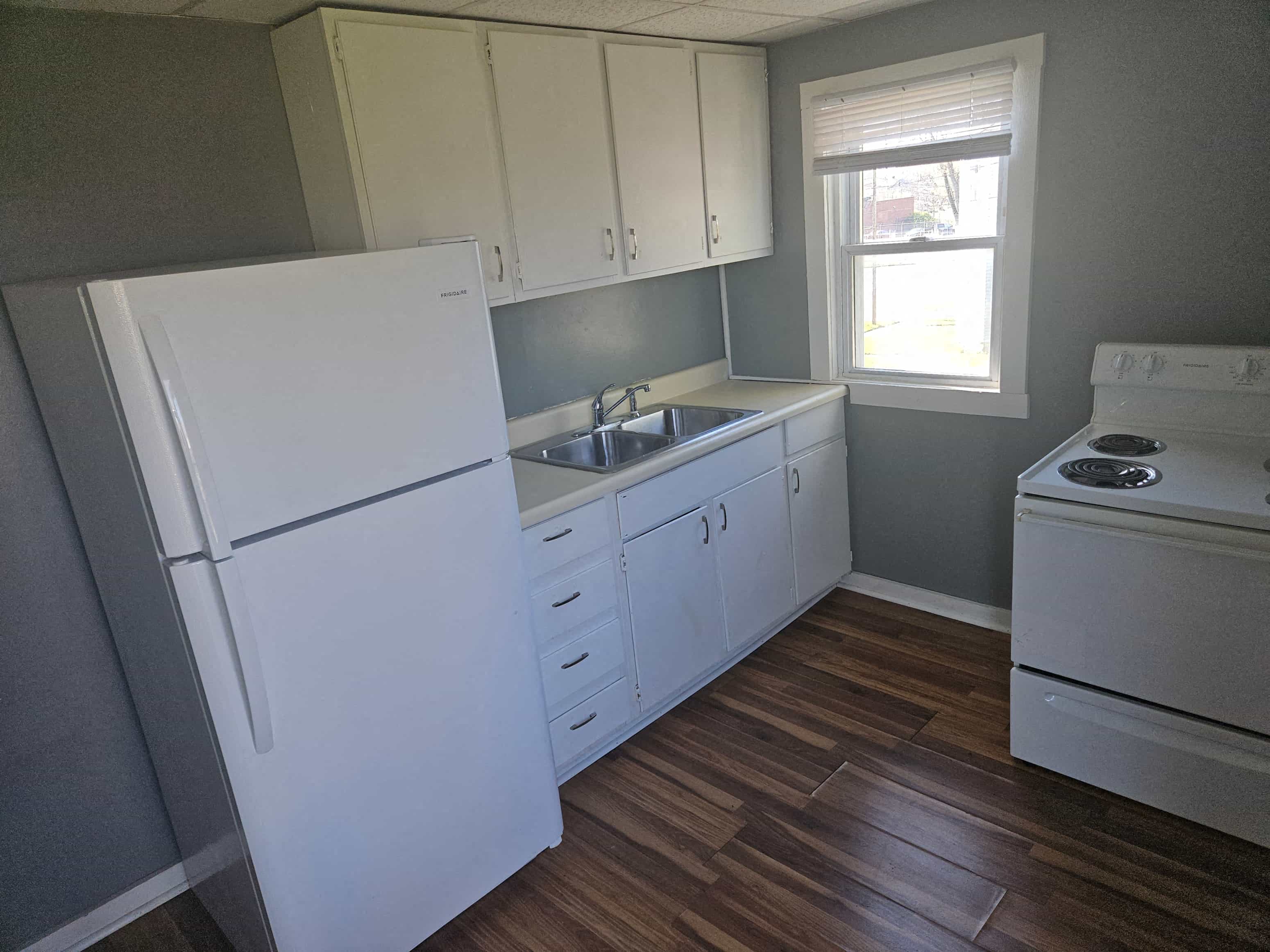 a kitchen with white cabinets and a sink and refrigerator
