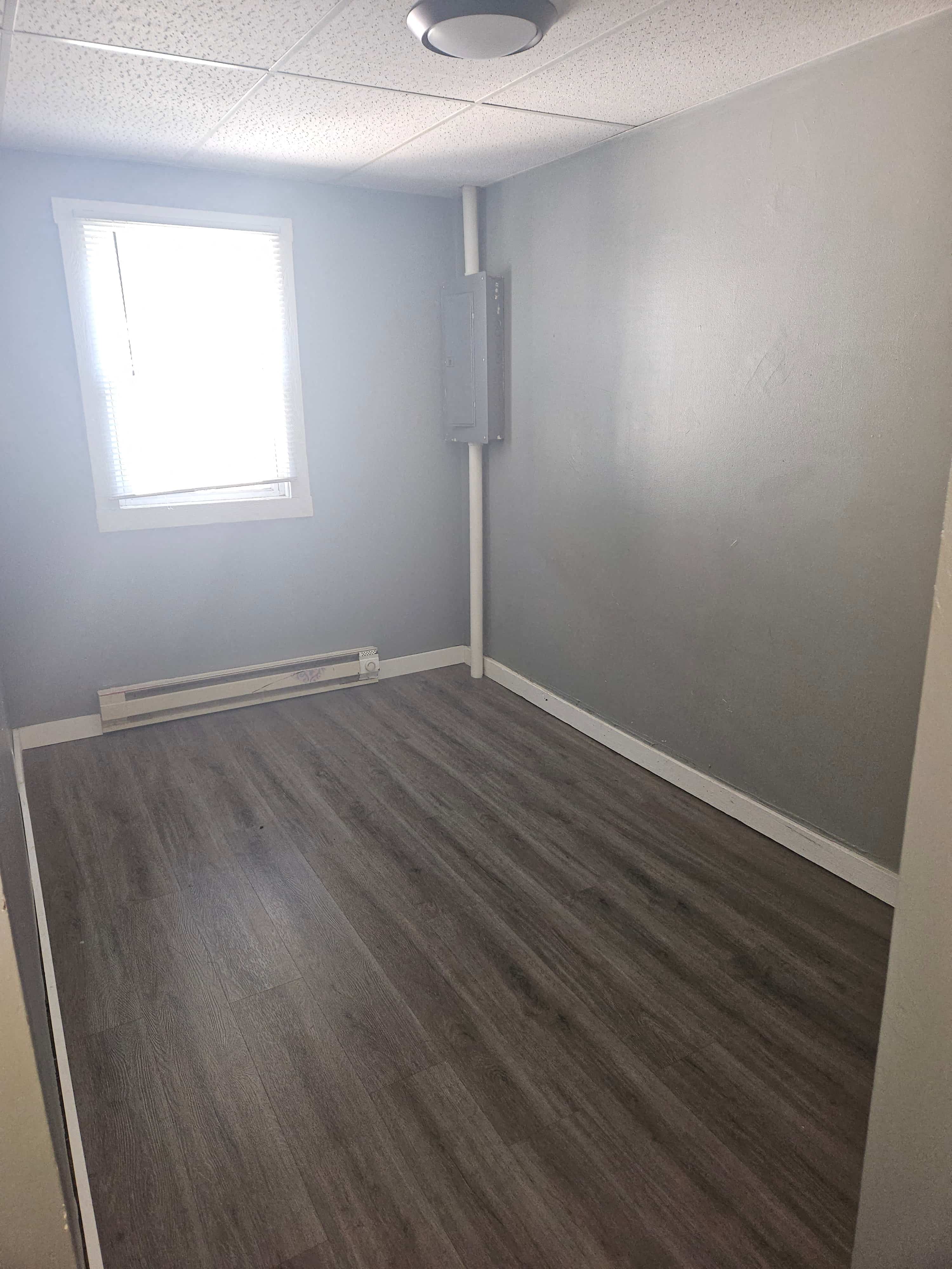 an empty room with wooden floors and a window