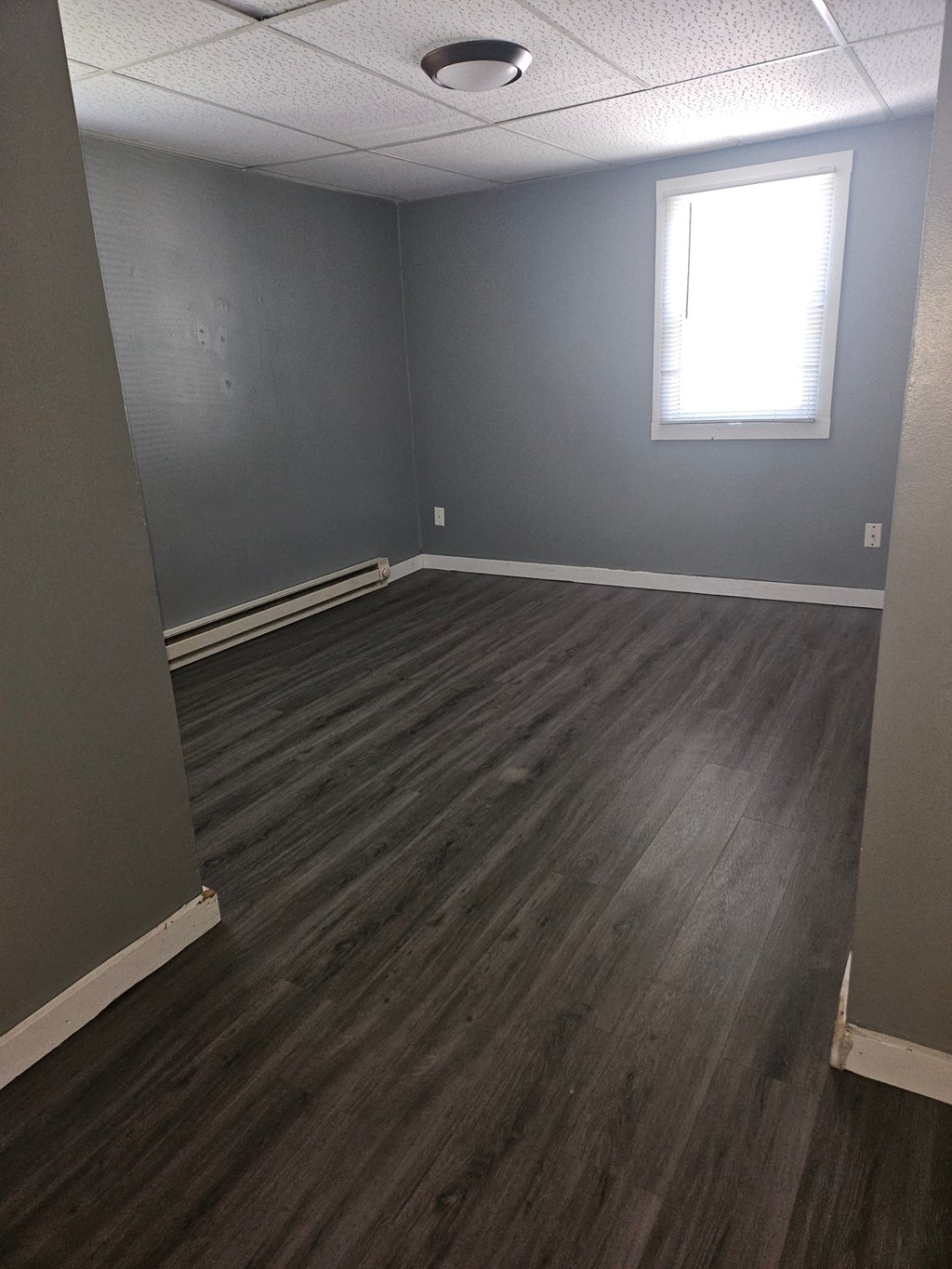 an empty room with wooden floors and a window