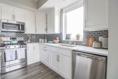 a white kitchen with stainless steel appliances and white cabinets