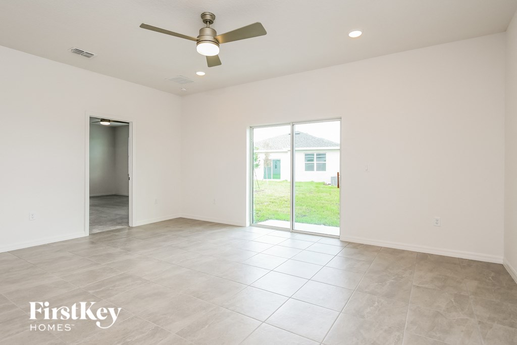 an empty living room with a ceiling fan and a sliding glass door