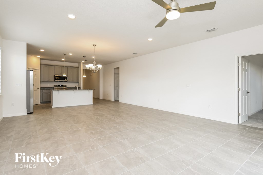 an empty living room and kitchen with a ceiling fan