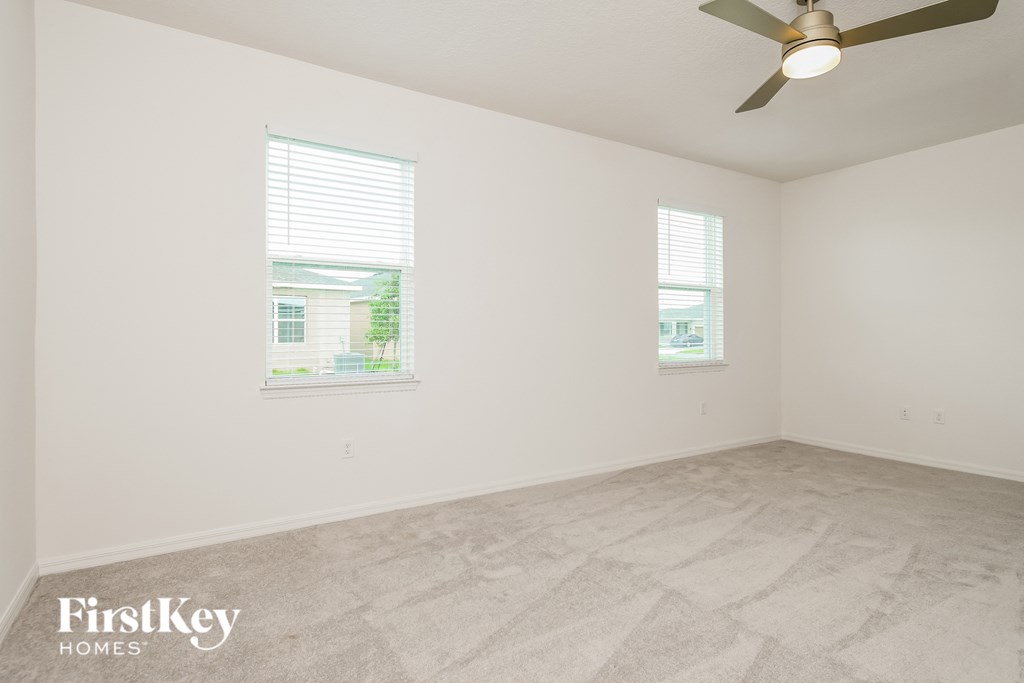 a living room with a ceiling fan and two windows